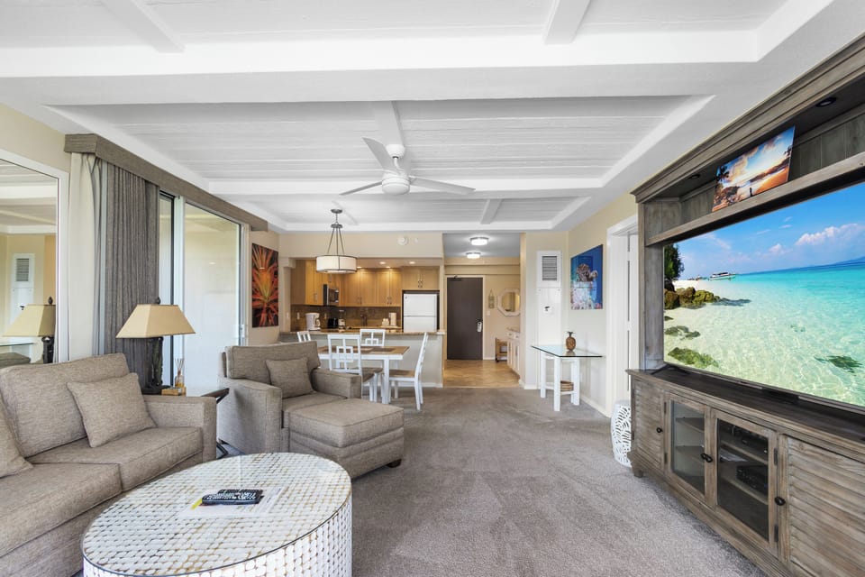 Unwind in your spacious, beautifully appointed living area with plush seating, ceiling fans, and a large flat-screen TV. The open layout flows into a fully equipped kitchen, perfect for relaxing after a day of adventure.