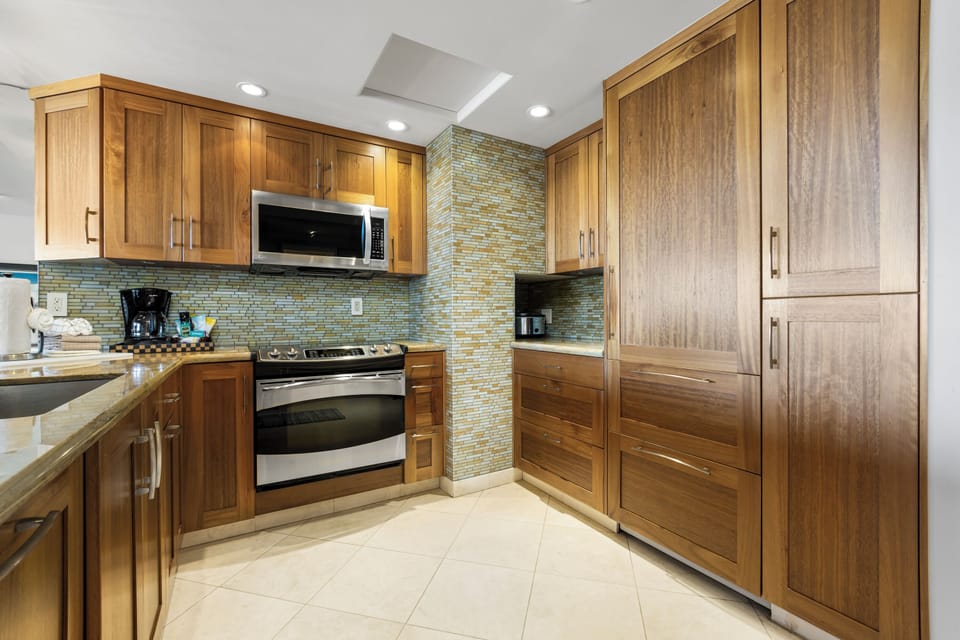 You'll love preparing meals in this fully equipped kitchen with warm wood cabinetry, modern appliances, and a stylish tile backsplash that adds a pop of color.