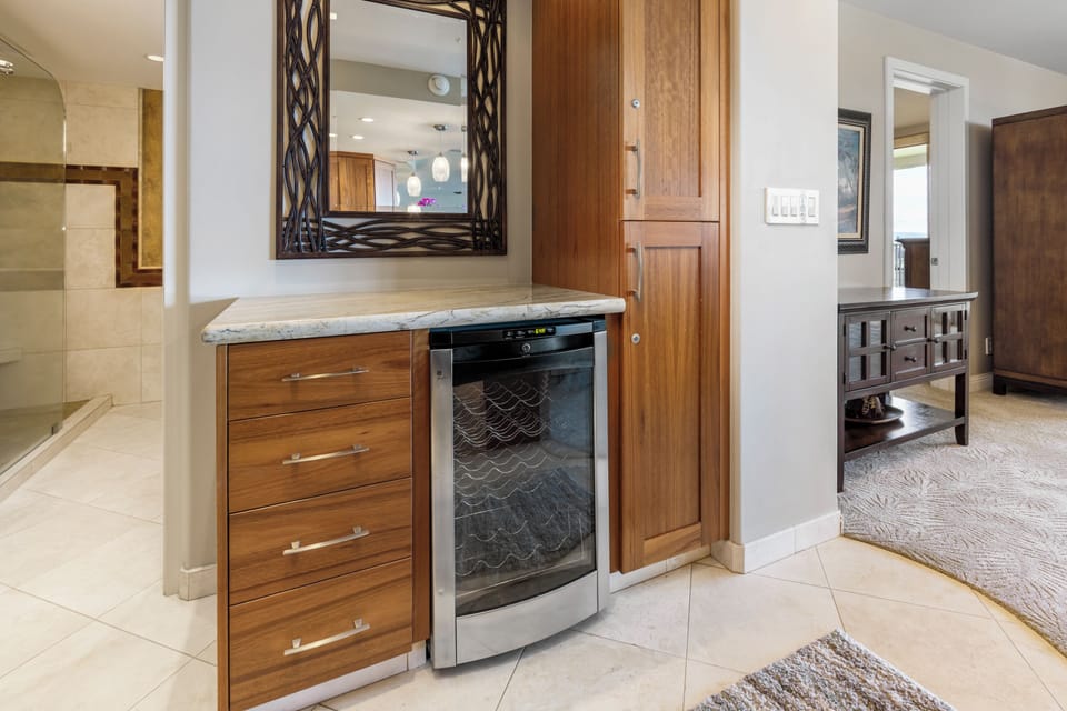 Your suite features a thoughtfully designed beverage station with a wine cooler, sleek storage drawers, and a mirrored vanity—perfect for unwinding after a day of adventure.