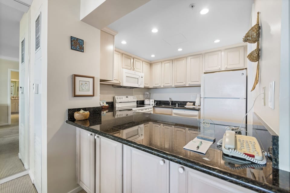 Your fully equipped kitchen features sleek granite countertops, modern white appliances, and ample cabinet space—perfect for preparing meals and enjoying a relaxed home-away-from-home experience.