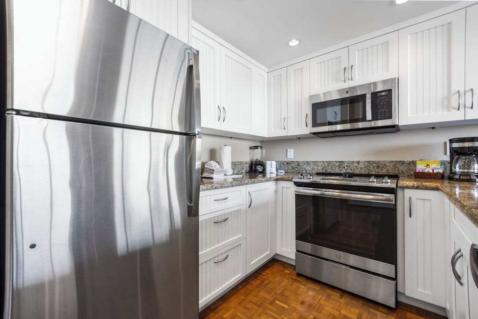 Your fully equipped kitchen features stainless steel appliances, granite countertops, and bright white cabinetry—perfect for preparing meals and enjoying your home away from home.