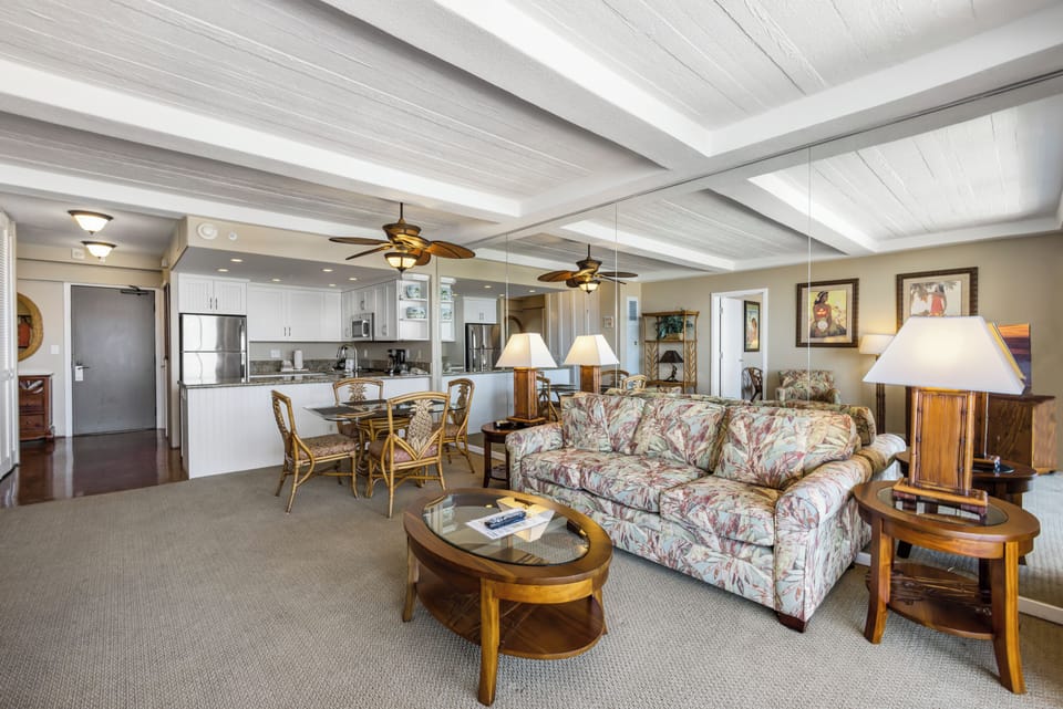 Step into your spacious island retreat, where ceiling fans stir tropical breezes above your open-concept living area. The fully equipped kitchen flows seamlessly into your dining and lounge spaces, all bathed in warm natural light.