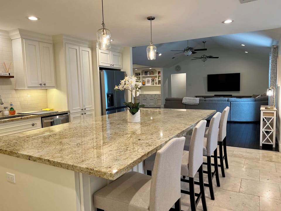 Large granite counter top island with 4-6 bar stools for casual meals.