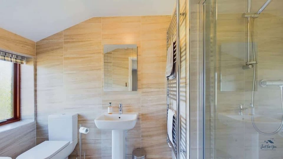 The private en-suite for the super king bedroom features a modern walk-in shower for a luxury holiday feel.
