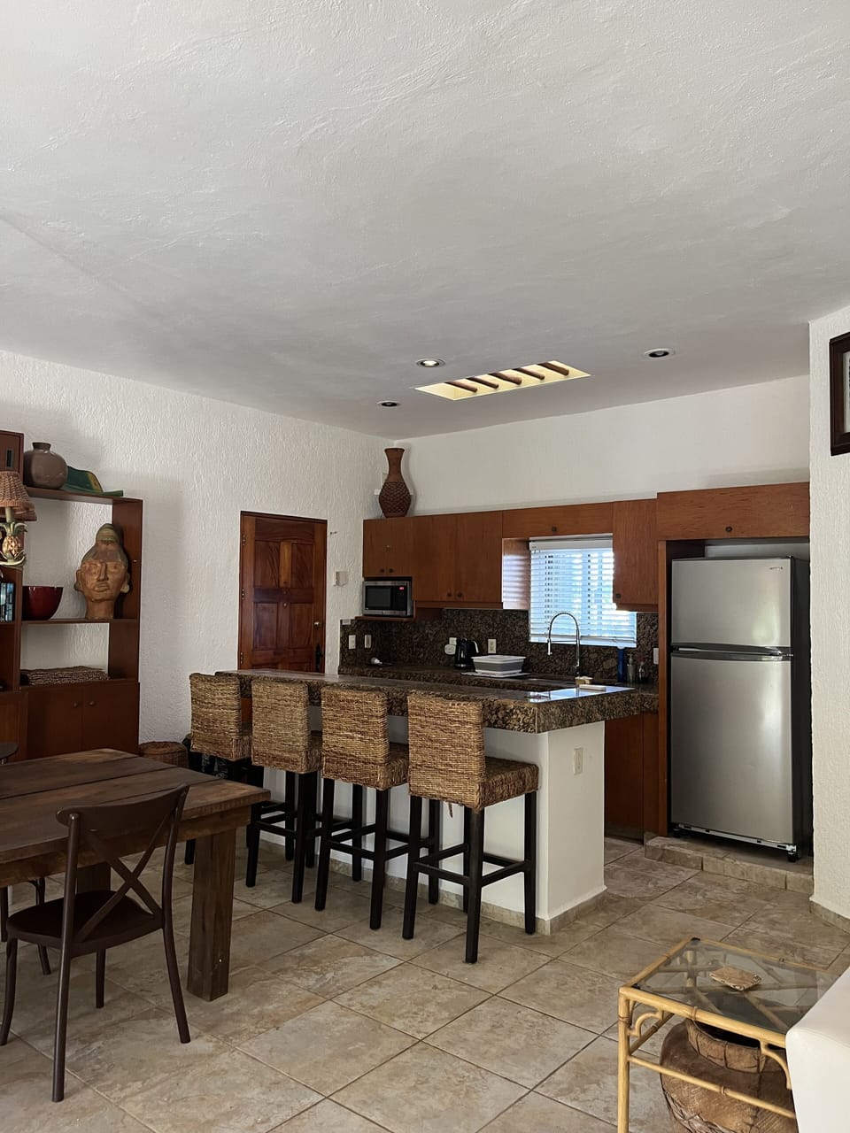 Full kitchen, breakfast bar, and dining table are in the spacious room.