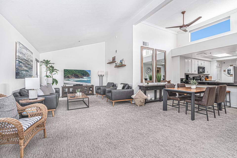 The living area includes sofa, side chairs, streaming tv, dining table with seating for 4, and kitchen beyond.
                