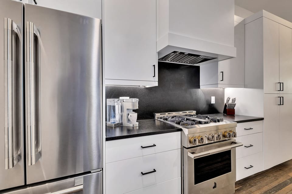 Bright galley kitchen w/ sleek finishes, stainless appliances & open flow to dining area