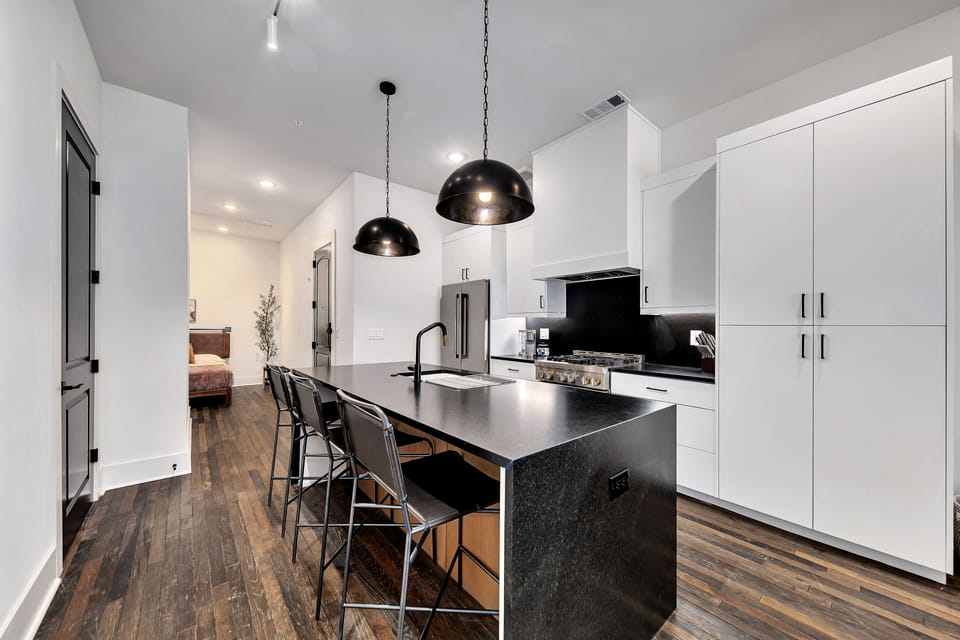Open dining area flowing into kitchen, accented by modern artwork & warm wood floors