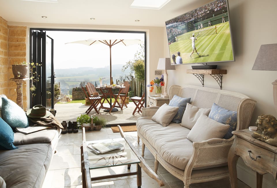Lower ground floor:  The garden room with exposed stone wall, large Smart TV with Netflix and bi-fold doors to garden