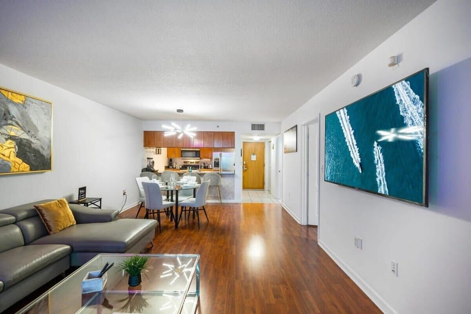 Modern open living area with a large wall-mounted television and dining space.