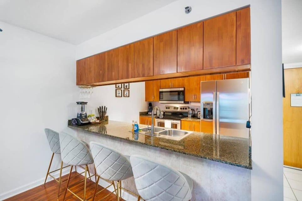 Modern kitchen with granite countertops and a breakfast bar with seating for four.