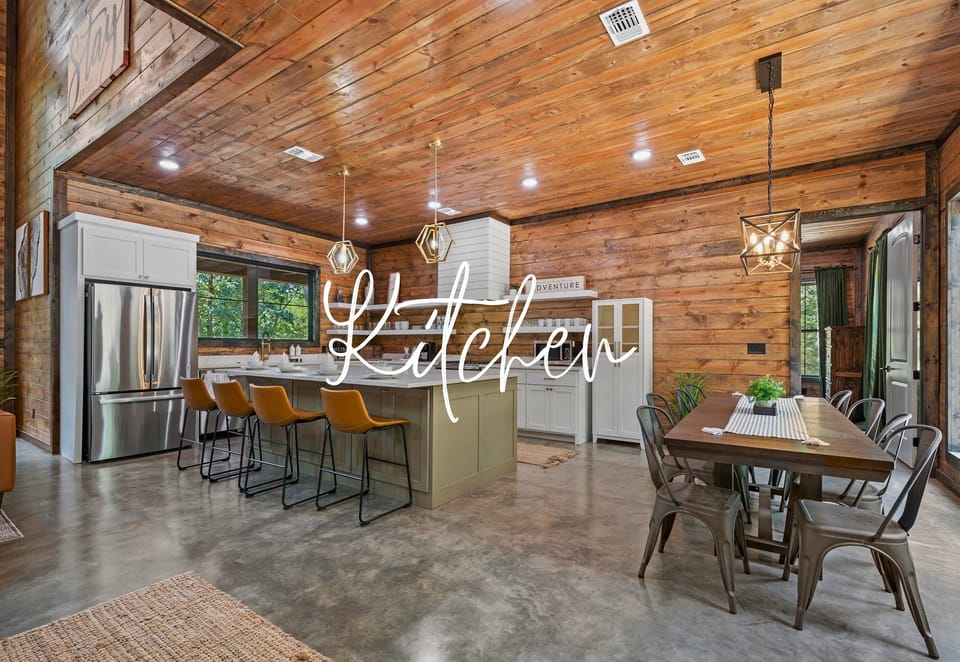A kitchen and dining space with high ceilings, wooden finishes and modern hanging lights