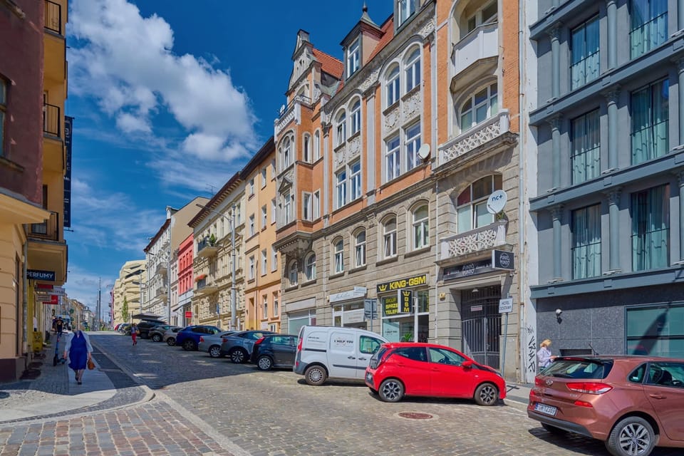 The building’s charming facade blends beautifully with the vibrant urban surroundings, offering a view of cobblestone streets and historic architecture.