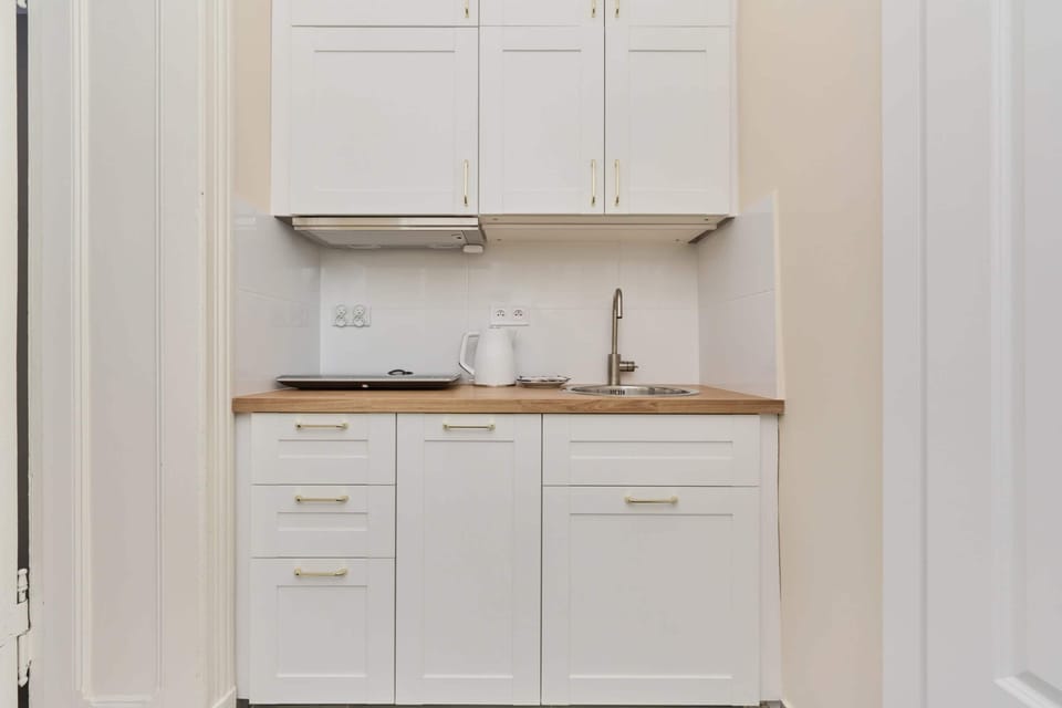 A minimalist white kitchen equipped with essential appliances, blending functionality with a polished design.