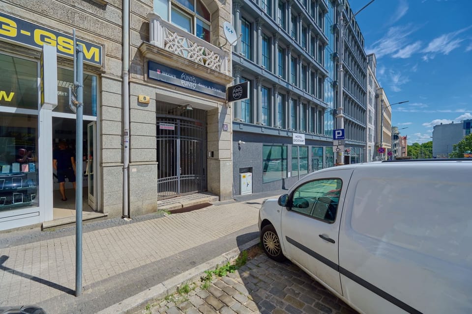 The building’s charming facade blends beautifully with the vibrant urban surroundings, offering a view of cobblestone streets and historic architecture.