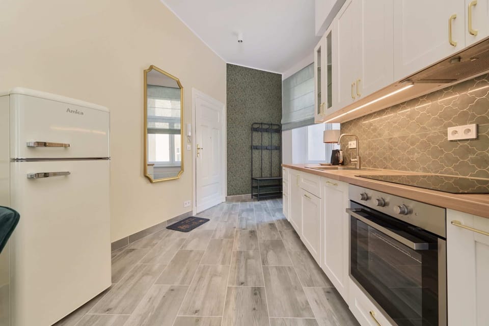 A modern kitchen with sleek light cabinetry, stainless steel appliances, and a tiled backsplash in neutral tones.