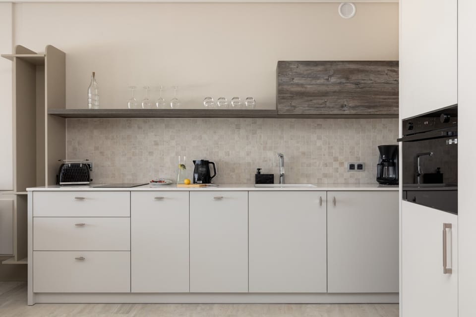 A fully equipped modern kitchen with white cabinets, tiled backsplash, and essential appliances.