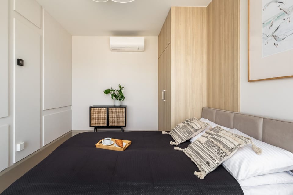 A cozy bedroom with a comfortable double bed, soft lighting, and warm wooden paneling.