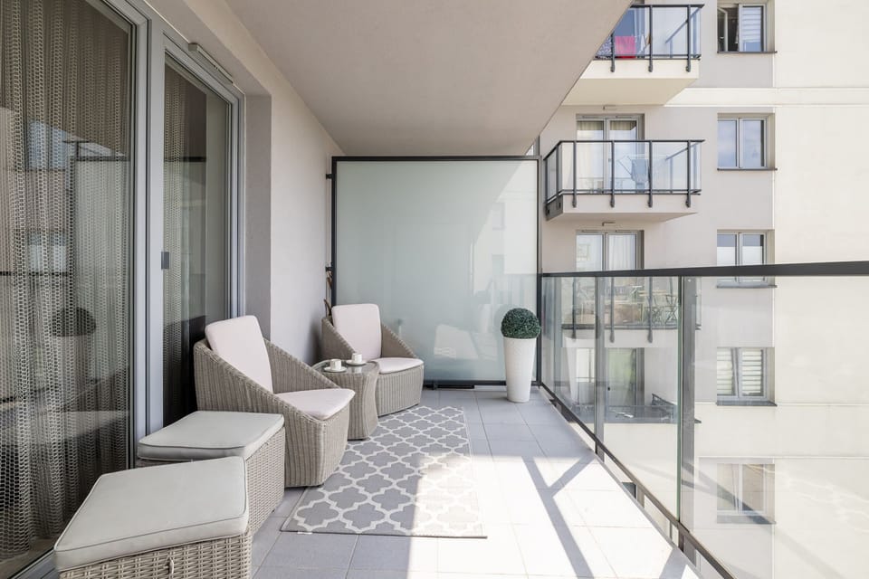 A spacious balcony with comfortable seating and a glass railing, offering a private outdoor retreat.

