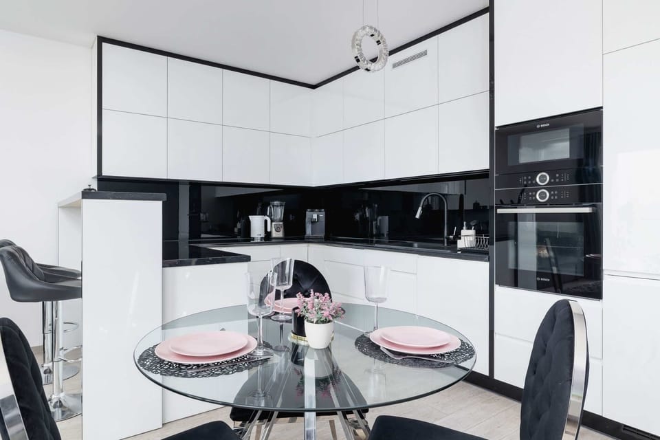 A sleek kitchen with black countertops, white cabinetry, and a round dining table, perfect for modern living.

