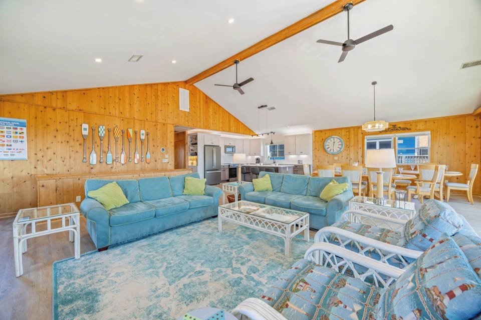 Sink into plush sofas and unwind in your spacious living room, with soaring ceilings, charming wood-paneled walls, and an open layout flowing into the kitchen and dining area.