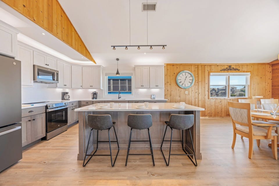 Your spacious kitchen boasts modern appliances, a large island with seating for gathering, and warm wood accents that create a welcoming mountain retreat vibe.