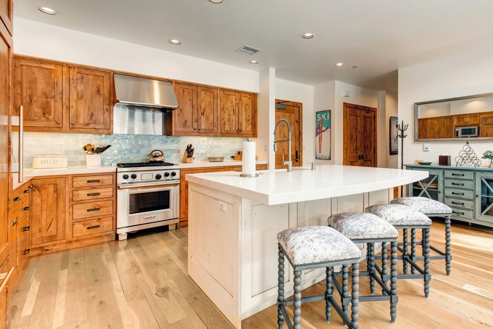 - Gourmet kitchen with Wolf range and designer backsplash for culinary flair
- Expanded view shows cozy cabin touches and curated mountain style décor
- Extra counter space and charming stools make this a heart of the home gathering spot