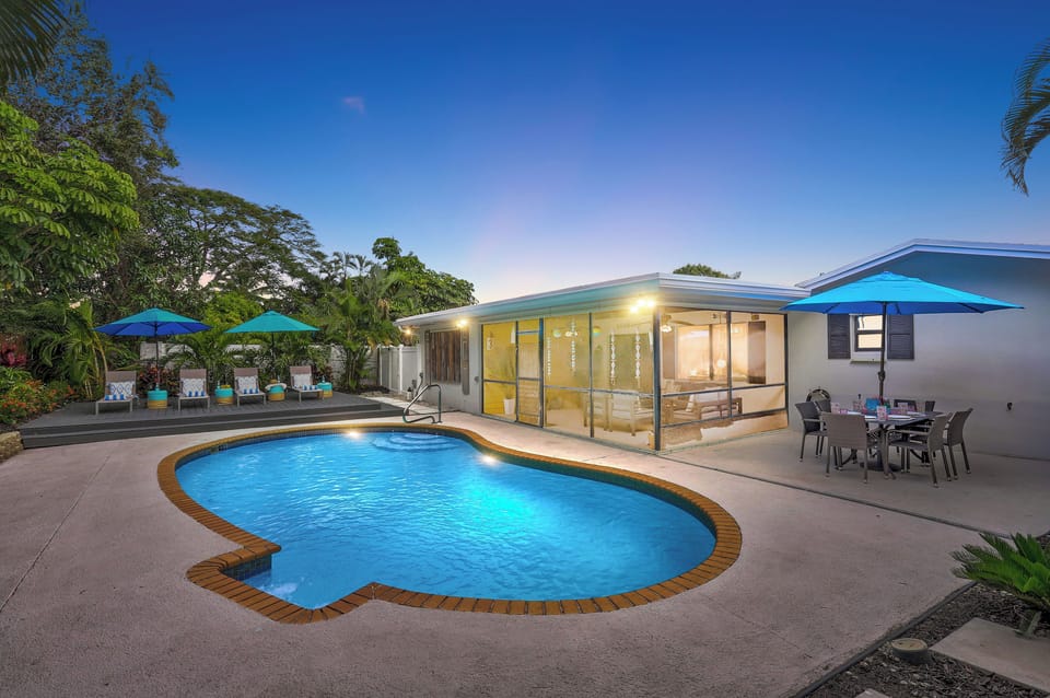 Unwind in your private oasis – sparkling pool and lush backyard glowing under the magical twilight sky.