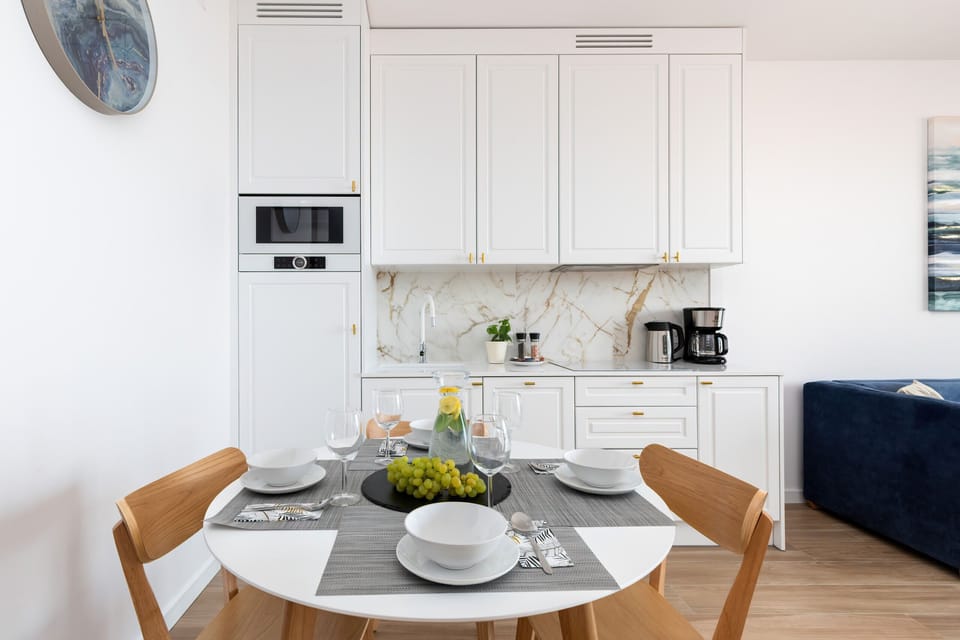 A modern kitchen with white cabinets, a round dining table, and a bright atmosphere.