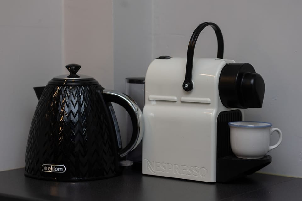 A sleek coffee and tea station featuring a modern coffee machine, a stylish kettle, and matching cups for a convenient start to the day.

