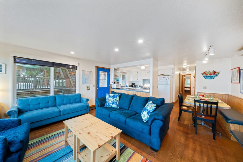 Living space with TV attached to the kitchen and dining area with ocean and mountain views.