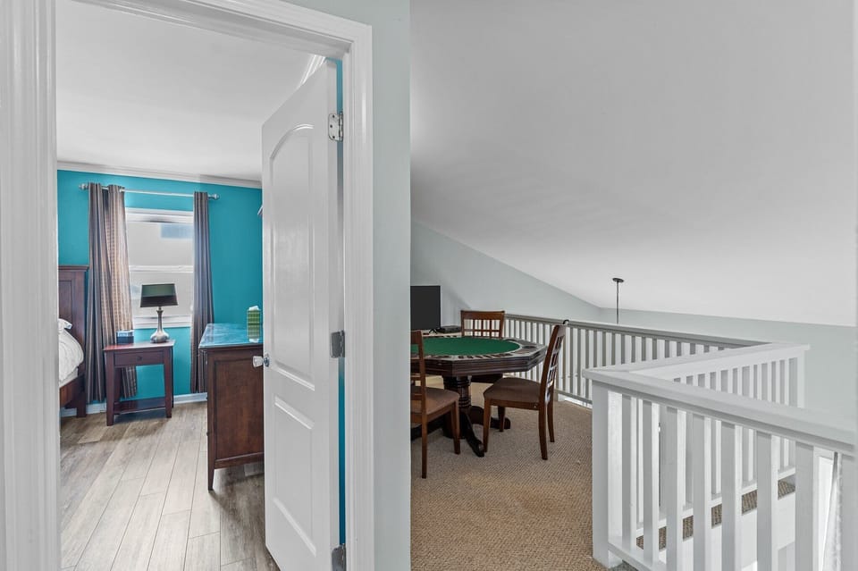Game room with a round poker table, four chairs, wall art, soft carpet, and a TV for laid-back coastal fun.