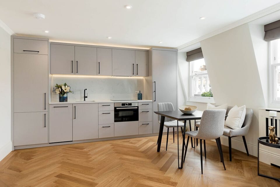 Kitchen & Dining Area — fully equipped straight-run kitchen with marble work surfaces, bespoke cabinetry, and hardwood flooring. Hob, oven, microwave, fridge, freezer, dishwasher, washer/dryer, coffee machine, kettle, toaster, and cooking utensils