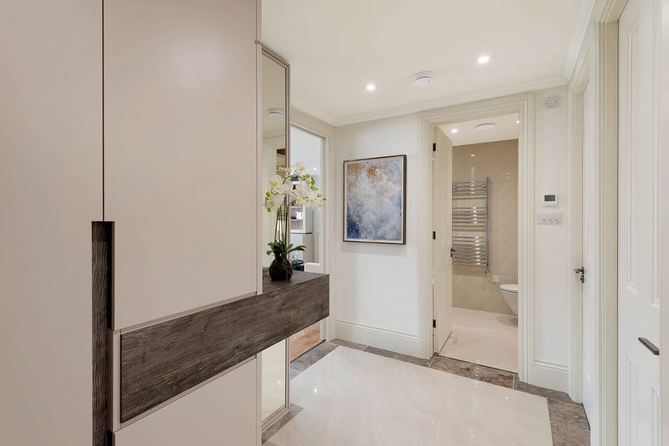 Entrance Hallway — tiled flooring, ceiling lights, and bespoke storage unit, leading through to the bedroom, living room, and bathroom