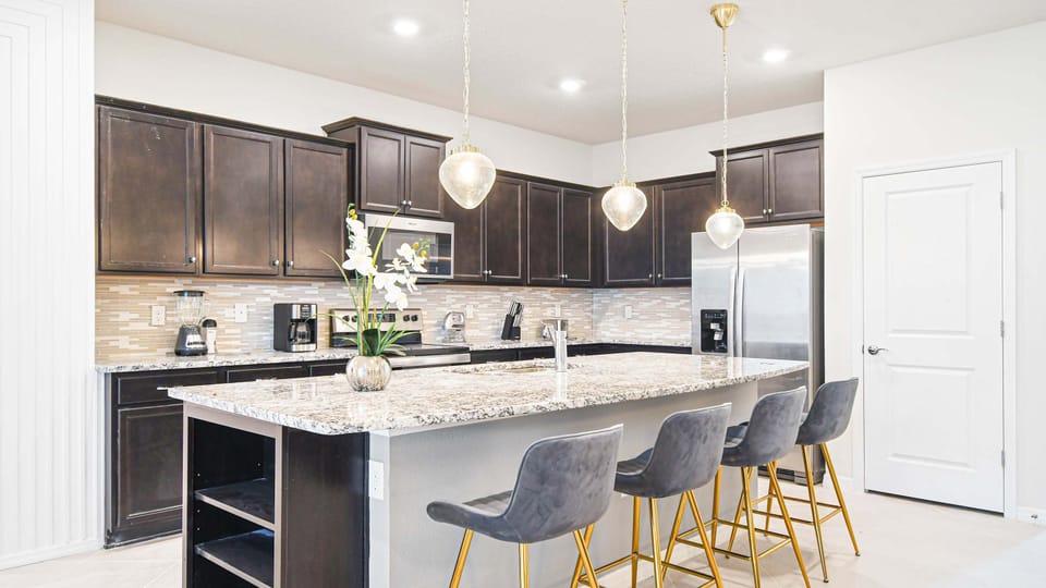 Stylish chef’s kitchen with granite island, modern lighting, and sleek finishes