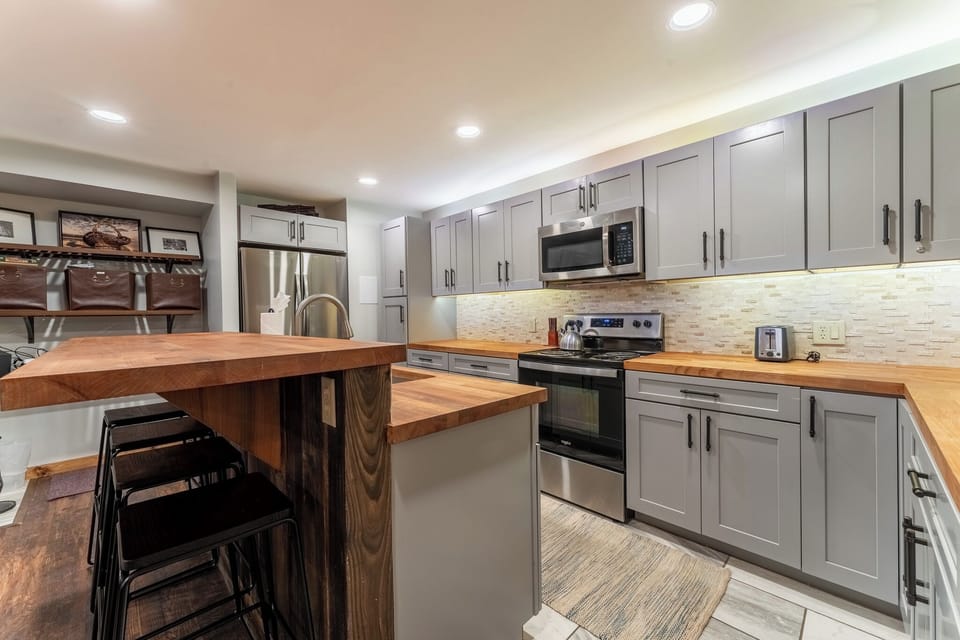 Cook your favorite meals in this spacious kitchen with stainless steel appliances, warm wood countertops, and a breakfast bar perfect for morning coffee.