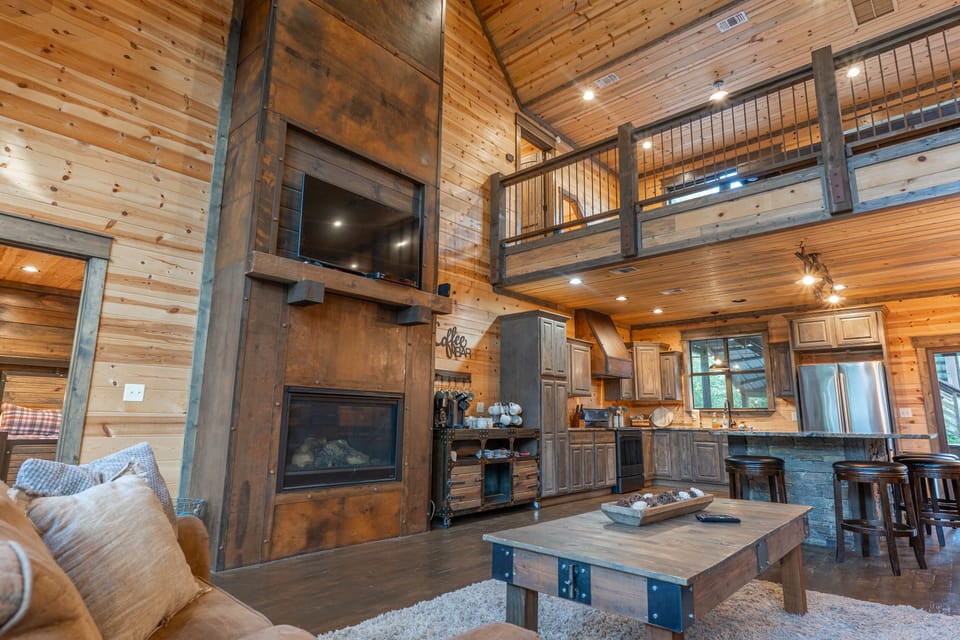 The grand room here at Wildcat Lodge features a custom metal wrapped two-story fireplace equipped with a large screen TV.