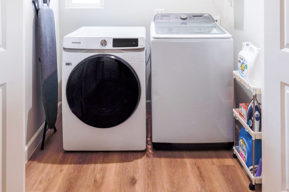 In-unit laundry area with washer and dryer and laundry essentials.