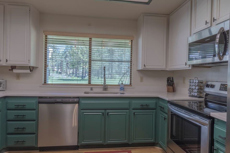 Bright kitchen with forest views, stainless appliances, and stylish cabinetry