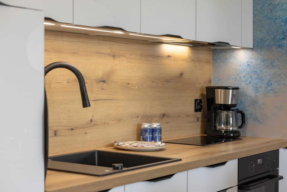 A stylish kitchen with wooden countertops, black fixtures, and high-quality appliances for a sleek and functional space.

