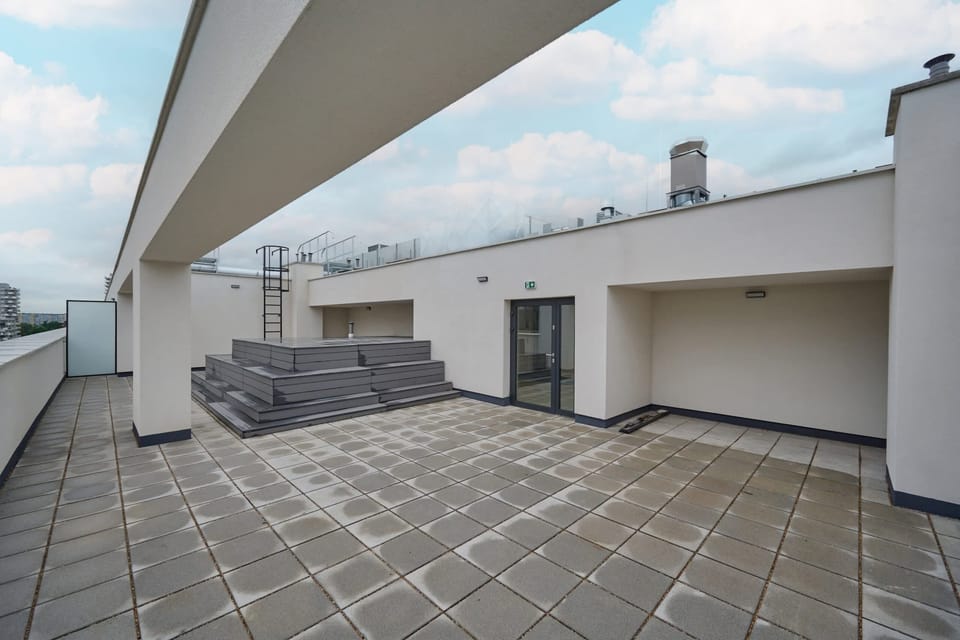 A spacious rooftop terrace with seating, offering a relaxing spot with views of the city skyline.

