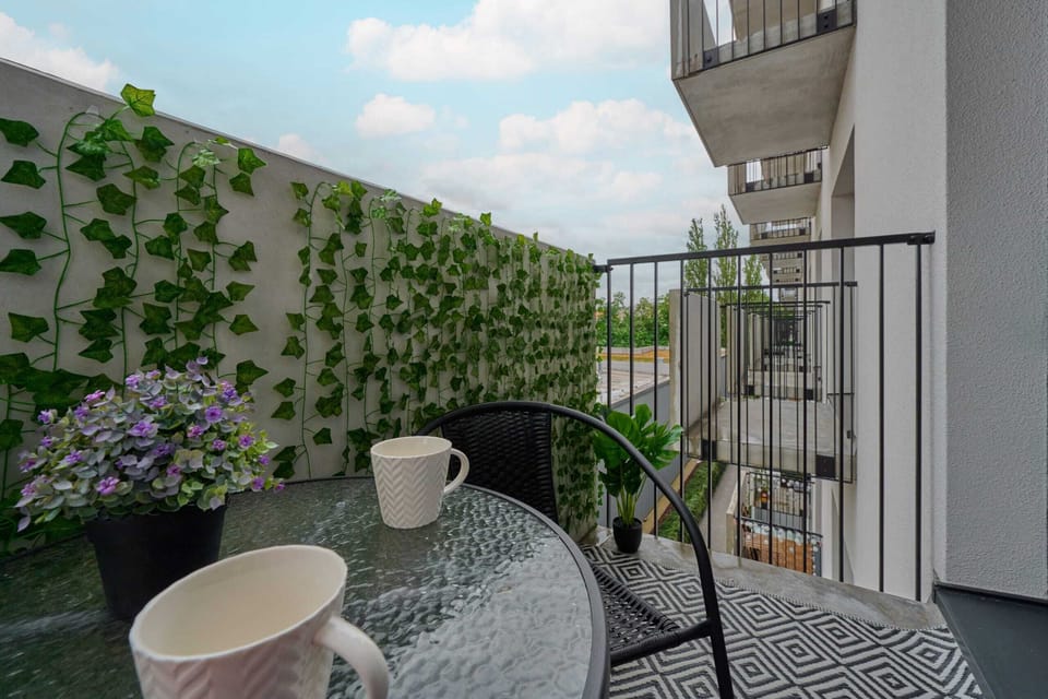 Another perspective of the balcony, featuring potted plants and a small table for enjoying coffee or a meal.

