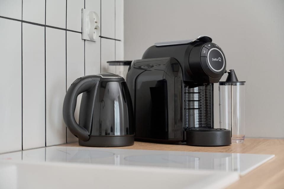 A coffee and tea station featuring a sleek coffee machine, mugs, and a bright countertop for convenience.







