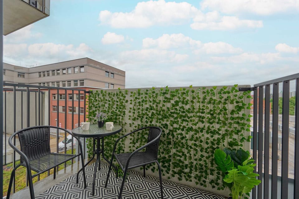 A charming balcony with a small table, two chairs, and lush greenery, ideal for enjoying a morning coffee or evening relaxation.

