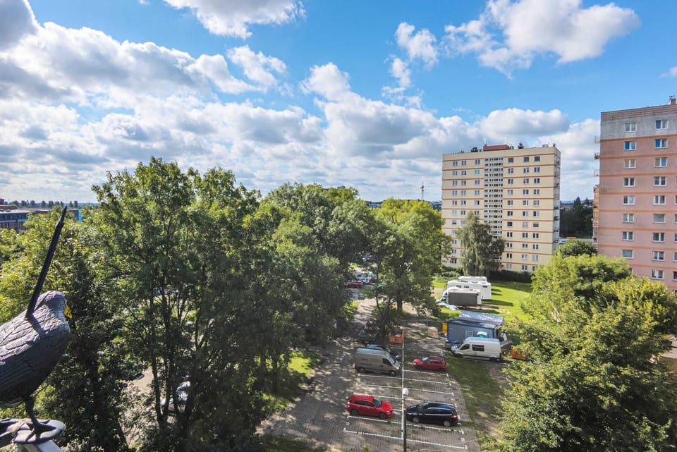A view from the apartment, showcasing the greenery and nearby urban surroundings under a clear blue sky.

