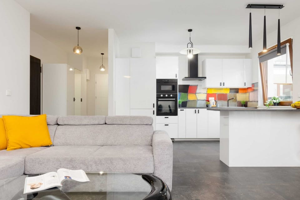 Another angle of the living room, showcasing its cozy seating, bright accents, and seamless connection to the kitchen.

