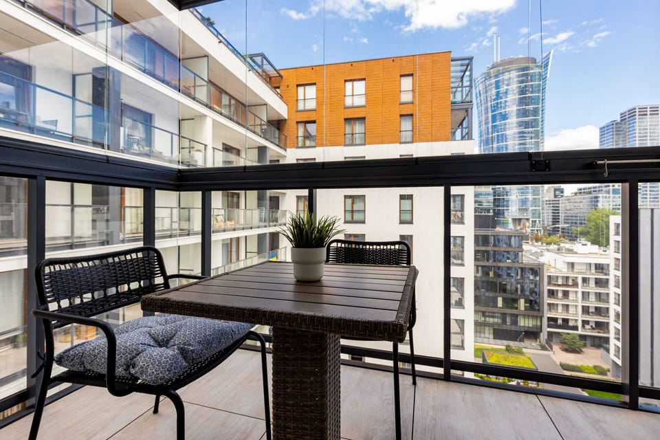 A private balcony with modern outdoor seating and a stunning view of the urban skyline.

