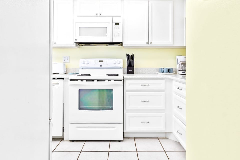 Fully equipped kitchen with white cabinetry, modern appliances, and bright lighting.