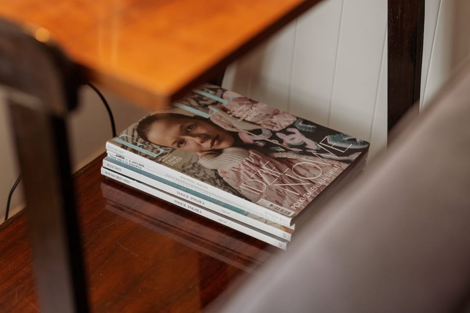 A close-up of magazines and books arranged neatly on the wooden coffee table, adding a homely feel to the space.

