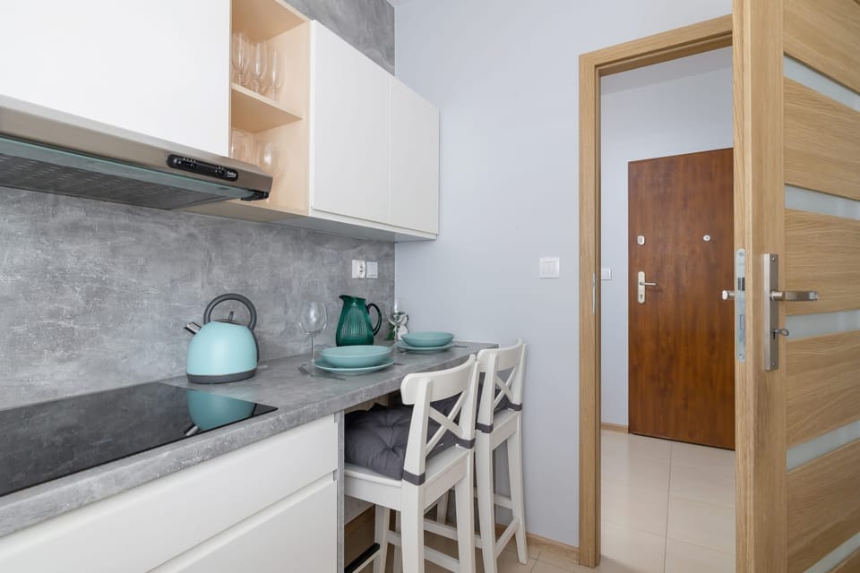 A compact yet functional kitchen corner with modern appliances and a dining setup for two.

